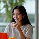 Profesional sedang snek di meja pejabat dengan laptop